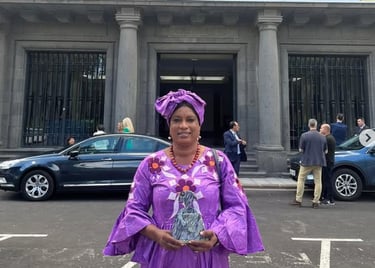una mujer con un vestido morado sujetando un premio con las dos manos