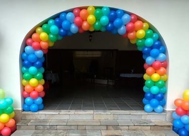 Arco de balões colorido na entrada de aniversário, criando ambiente alegre e acolhedor.