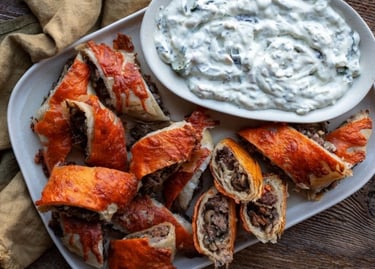 Plate of phyllo beef wellington bites with spinach dip by Dan Clapson