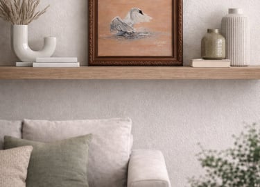 Framed swan oil painting displayed on a wooden floating shelf above a neutral living room sofa.