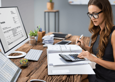 Une femme assise à son bureau, utilisant une calculatrice