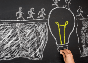 a person holding a light bulb in front of a chalkboard