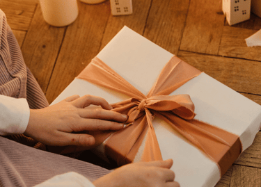 a person holding a present box with a bow