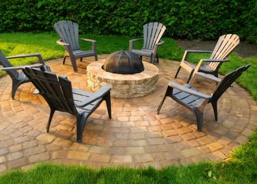 Foyer extérieur circulaire en pierre avec chaises Adirondack sur terrasse en pavés par M2 Paysage