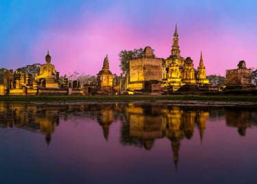 Ruinas iluminadas del templo Wat Mahathat en el Parque Histórico de Sukhothai al anochecer, refleján