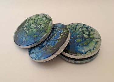 Handmade round gypsum coasters featuring blue and green abstract fluid acrylic pour art.