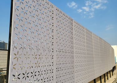 Laser cut metal privacy screen with a decorative floral pattern on a modern outdoor construction site.