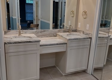 Modern bathroom double vanity with white cabinets, marble countertops, and large framed mirrors.