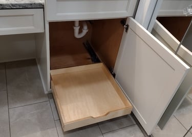 White bathroom vanity with marble countertop and a wooden pull-out cabinet organizer drawer.
