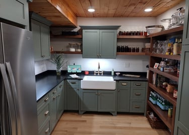 Modern rustic kitchen with sage green cabinets, farmhouse sink, and open wood shelving.
