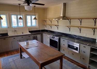 Modern farmhouse kitchen with grey cabinets, marble countertops, open shelving, and a rustic wooden island.