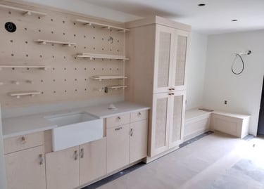 Custom light wood mudroom cabinets with an apron front sink and a large pegboard wall organizer.