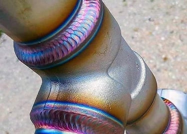 Precision TIG welding on a titanium pipe joint with colorful heat tint and clean stack of beads.
