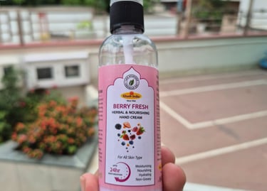 a person holding a bottle of berryfruit hand cream