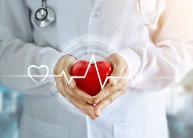 A doctor in a white coat holding a red heart with a digital pulse line for cardiac health care.