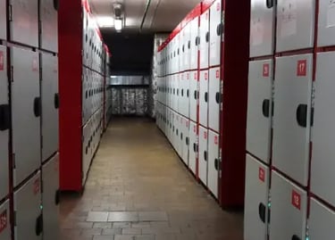 Narrow hallway lined with red and white secure storage lockers for public use.