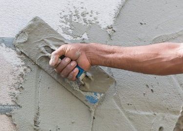 A person applying stucco to a wall.