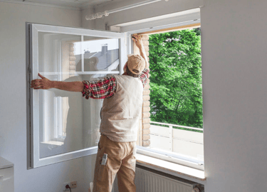 A window being installed into a wall by a person.