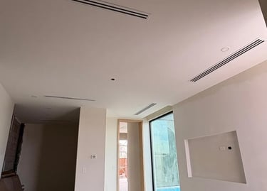 Construcción interior moderna con plafones de panel de yeso blancos y difusores lineales HVAC