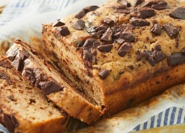 Freshly baked sliced banana bread topped with dark chocolate chunks at create perfectly