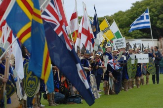Viking reenactors holding diverse international flags and shields during a historical festival parade.