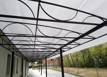 Modern outdoor polycarbonate awning with a black metal frame and decorative arches.