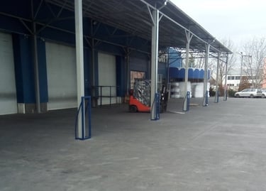 Red forklift parked under a covered loading dock at an industrial warehouse facility.