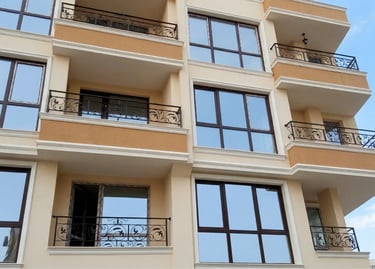 Modern apartment building with elegant wrought iron balcony railings and large glass windows.