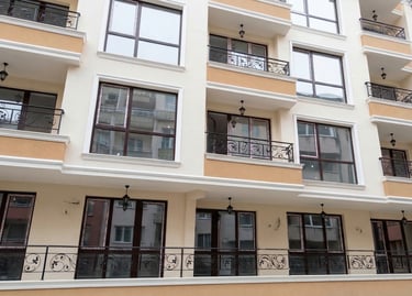 Modern apartment building facade with wrought iron balconies and large glass windows.