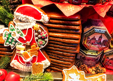 Hand-decorated gingerbread Santa and other spiced biscuits, with festive tins and pine cones, for a Christmas market display.