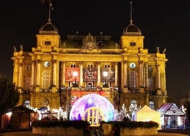 The Croatian National Theatre in Zagreb illuminated at night with festive Christmas market decorations.