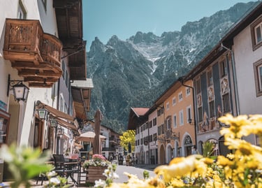 Traditional Bavarian village street in Mittenwald with colorful houses and the Karwendel mountains.