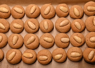 Freshly baked homemade almond cookies topped with whole blanched almonds on a baking sheet.