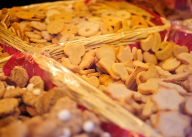 Assorted gourmet butter cookies and shortbread biscuits in rustic wicker baskets at a bakery market stall.