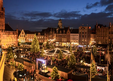 Aerial view of the festive Bruges Christmas market at night with glowing lights and trees.