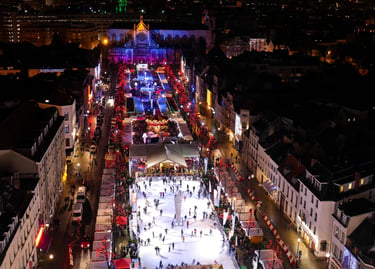 Night aerial view of the Brussels Christmas market with ice skaters and festive lights.