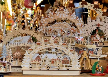 Handcrafted German wooden Christmas candle arches and village scenes at a festive holiday market.