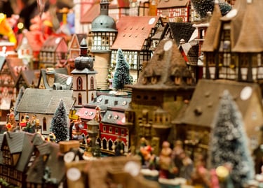 Handcrafted miniature German Christmas village with traditional timber-framed houses and snow-covered trees.