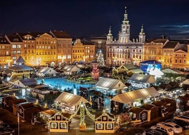 Aerial view of a festive European Christmas market with lit stalls and an ice rink at night.