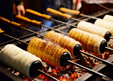 Traditional Hungarian chimney cakes roasting over hot coals at a European Christmas market.