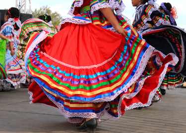 Dancers perform Mexican folkloric dance in vibrant, colorful ribbon skirts and traditional Jalisco dresses.