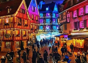 Crowds walking through a festive European Christmas market with colorful illuminated half-timbered houses.