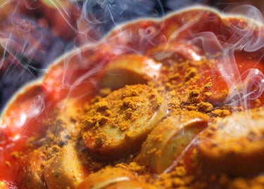 Close-up of steaming hot German currywurst sliced sausage topped with spicy tomato sauce and yellow curry powder.
