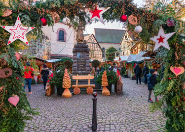 Traditional Christmas market in Eguisheim, France, featuring festive star decorations and wooden stalls.