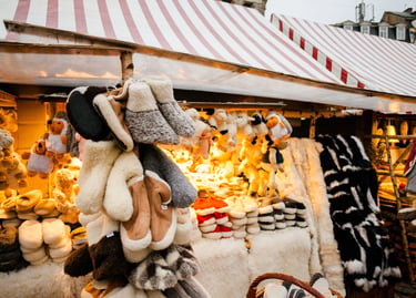 Handmade wool slippers and plush sheep toys displayed at a festive outdoor Christmas market stall.