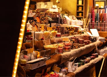 Handmade candles and aromatic incense displayed at a festive outdoor European Christmas market stall.