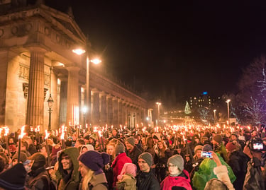 Crowds carry flaming torches past the Royal Scottish Academy during the Edinburgh Hogmanay torchlight procession.