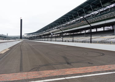 Indianapolis Motor Speedway finish line bricks and grandstands on a cloudy day.