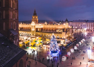 Krakow Main Market Square at night featuring the Christmas market, illuminated Cloth Hall, and festive tree.