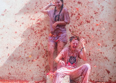 Two happy women covered in red pulp during the La Tomatina tomato festival in Spain.